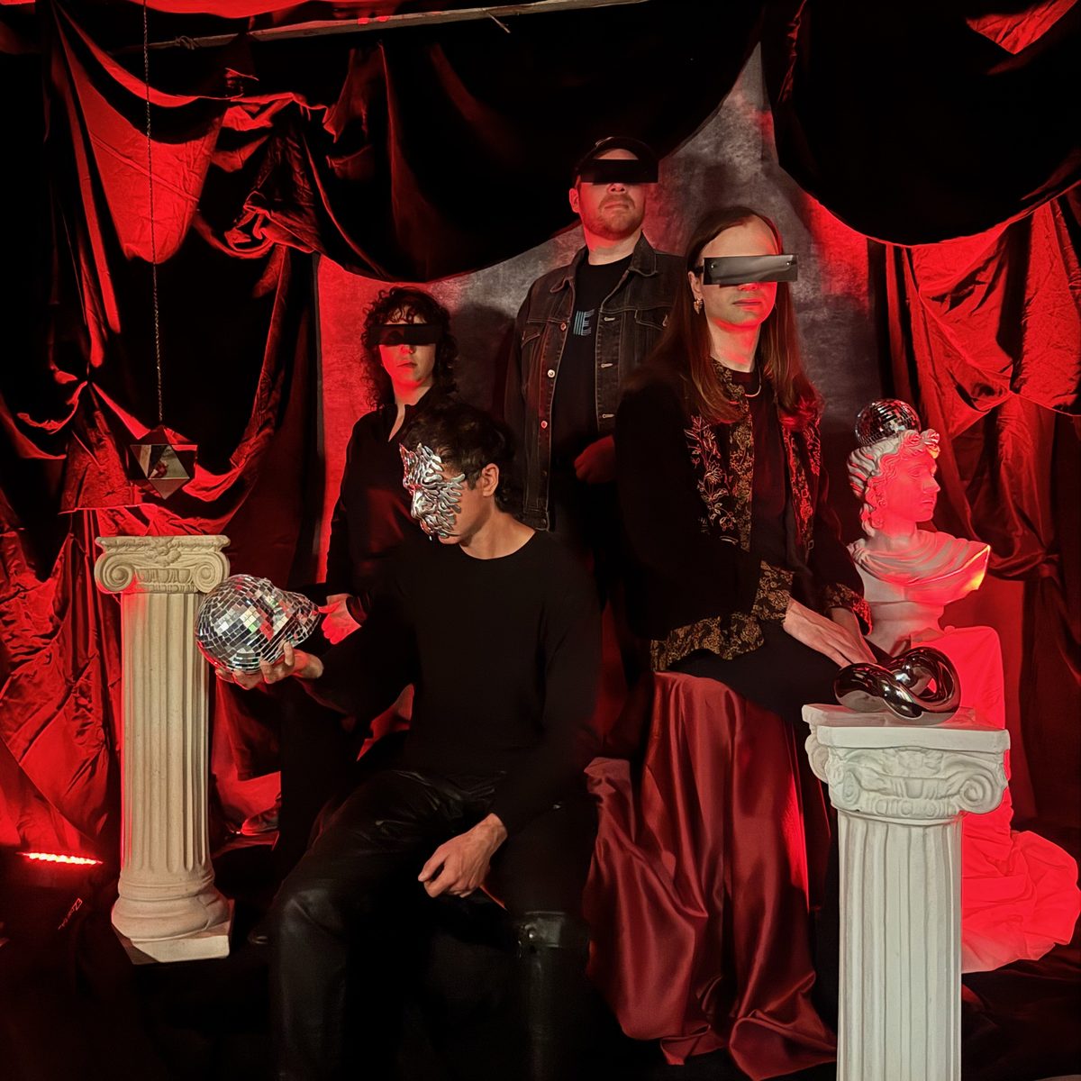 The four members of Alan Onymous, eyes hidden behind black bars and a silver mask, posed among classical columns and a bust under red light